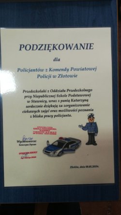 Zdjęcie przedstawia podziękowania przedszkolaków Oddziału Niepublicznej Szkoły Podstawowej w Stawnicy złożone na ręce sierżanta sztabowego Damiana Pachuca o następującej treści &quot;podziękowanie dla policjantów Komendy Powiatowej Policji w Złotowie. Przedszkolaki z Oddziału Przedszkolnego przy Niepublicznej Szkole Podstawowej w Satwnicy , wraz z panią Katarzyną serdecznie dziękują za zorganizowanie ciekawych zajęć oraz możliwość poznania z bliska pracy policjant&quot;. Na dole podziękowań pieczątka pani dyrektor placówki oraz wychowawcy umieszczona pod wizerunkiem policjanta oraz rysunkiem policyjnego radiowozu.