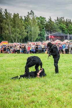 Policjanci obezwładniają niebezpiecznego przestępcę w trakcie pokazu w Zakrzewie. Pozorant leży na trawniku funkcjonariusze zakładają mu kajdanki