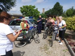 DZIELNICOWY, STOJA PRZY RADIOWOZIE Z KOBIETAMI ROWERZYSTKAMI, SENIORKAMI