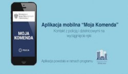 Baner promujący aplikacje Moja Komenda przygotowany przez MSWiA. Po lewej stronie smartfon z zainstalowaną aplikacją