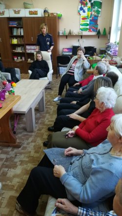 Uczennica Klasy mundurowej czyta seniorom łamigłówkę dotycząca ich bezpieczeństwa