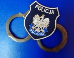 Naszywka z napisem Policja leży na  kajdankach