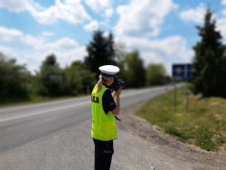 Policjantka ruchu drogowego wykonuje pomiar prędkości jadących pojazdów