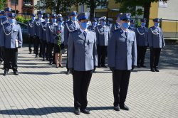 dwóch policjantów w umundurowaniu galowym stoi przed kolumną awansowanych oczekując na wręczenie rozkazu na pierwszy stopień policyjny starszego posterunkowego