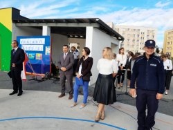 policjantka stoi na placu szkoły i wita uczniów w nowym roku szkolnym