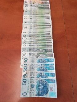 Zabezpieczone przez policjantów pieniądze ułożone zostały na stole znajdują się tam banknoty 50 złotowe, 100 złotowe i 200 złotowe