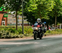 Policjant służby ruchu drogowego porusza się drogą na policyjnym motocyklu służbowym