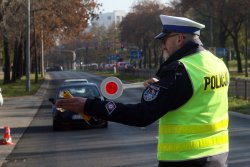 Na zdjęciu widać funkcjonariusza Policji wydziału Ruchu Drogowego który w ręku trzyma tarczę do zatrzymywania pojazdów oraz urządzenie do badania stanu trzeźwości osób, wydaje polecenie kierującemu pojazdem do zatrzymanie się i zjechania na pobocze