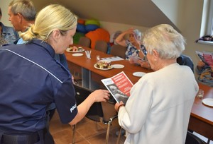 Policjantka przekazuje ulotkę seniorce