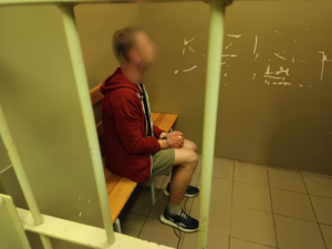 Zatrzymany mężczyzna siedzi w pomieszczeniu z założonym kajdankami na rękach